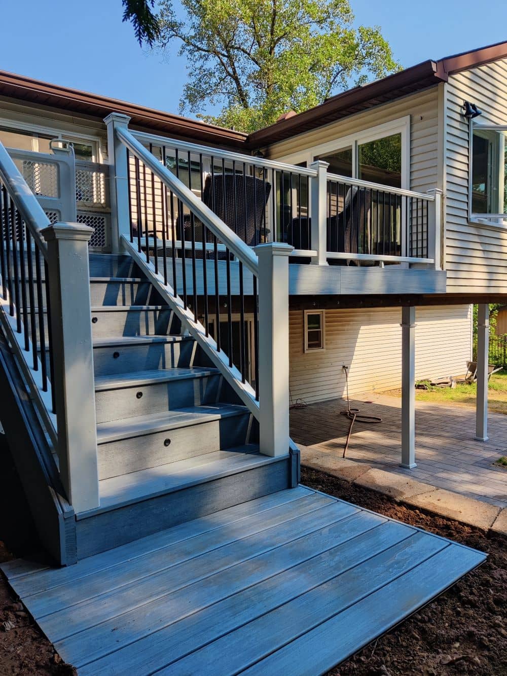 After photo of a full deck rebuild by True Built Construction, showing a large wooden deck spanning the entire width of a modern home, featuring natural wood tones and a clear protective railing