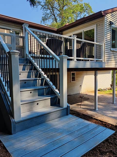 After photo of a full deck rebuild by True Built Construction, showing a large wooden deck spanning the entire width of a modern home, featuring natural wood tones and a clear protective railing